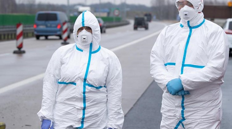 Mitarbeiter des polnischen Rettungsdienstes stehen mit Schutzkleidung an an einem Grenzkontrollpunkt. Foto: Sebastian Kahnert/dpa-Zentralbild/dpa