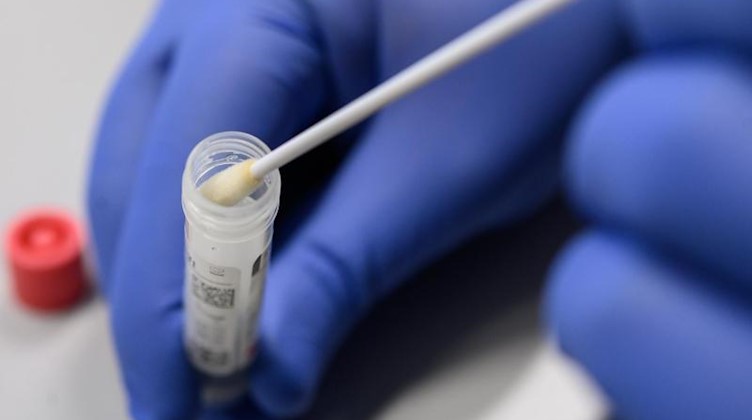 Ein Mann zeigt einen Abstrich für das Testverfahren auf das Virus SARS-CoV-2. Foto: Sebastian Gollnow/dpa/Symbolbild