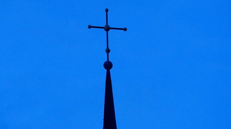 Ein Kirchenkreuz in der Abenddämmerung. Foto: picture alliance / dpa / Archivbild