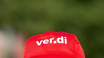Ein Mann trägt eine Mütze mit dem Verdi Logo. Foto: Christophe Gateau/dpa/Symbolbild