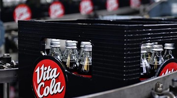 Nach der Abfüllung von Vita Cola werden Flaschen in Kästen auf der Bandanlage transportiert. Foto: Martin Schutt/dpa-Zentralbild/dpa