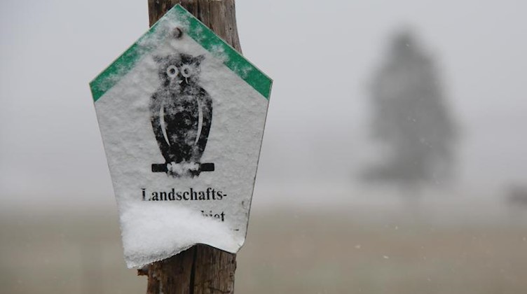 Blick auf ein verschneites Hinweisschild vor einem Feld in Hasselfelde. Foto: Matthias Bein/dpa-Zentralbild/ZB