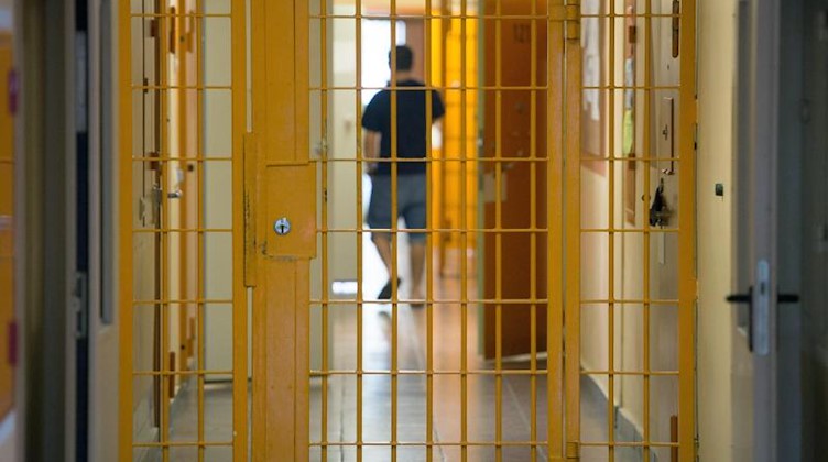 Ein Mann geht in einer Justizvollzugsanstalt hinter einer verschlossenen Gittertür einen Gang entlang. Foto: Sebastian Kahnert/dpa-Zentralbild/dpa/Archivbild