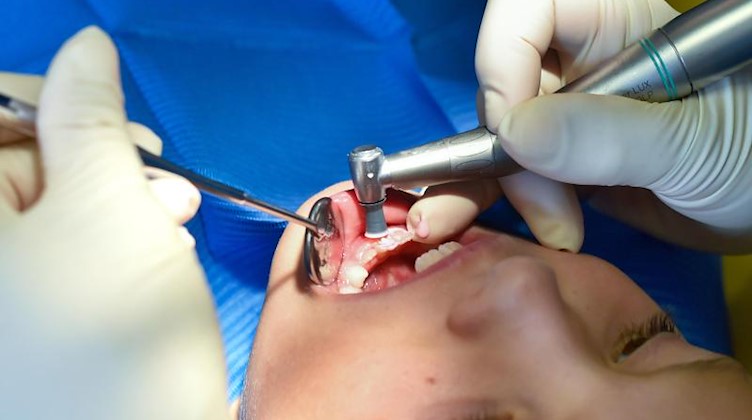 Ein Mädchen wird von einer Zahnärztin behandelt. Foto: Patrick Pleul/zb/dpa/Symbolbild/Archivbild