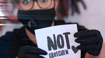 Christin Popella, Fleischermeisterin bei Popella Genusshandwerk in Aue, positioniert in ihrer Metzgerei ein Glas für Trinkgelder. Foto: Hendrik Schmidt/dpa-Zentralbild/ZB/Archivbild