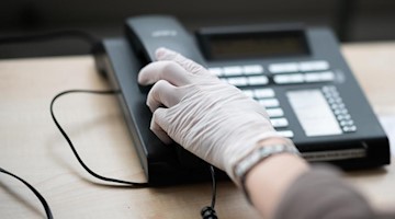 Eine Telefonseelsorgerin greift nach einem Telefonhörer. Foto: Daniel Reinhardt/dpa/Symbolbild