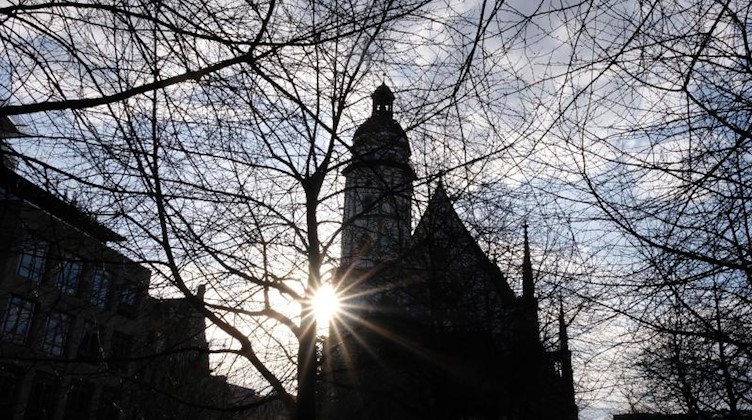 Die Sonne strahlt an der Thomaskirche hinter noch kahlen Bäumen. Foto: Sebastian Willnow/dpa-Zentralbild/dpa/Archivbild