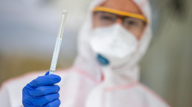 Ein Mitarbeiter hält einen Abstrich in der Hand, der benutzt wird, um einen Test auf das Coronavirus durchzuführen. Foto: Sebastian Gollnow/dpa/Symbolbild