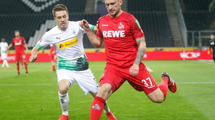 Der Kölner Toni Leistner (r) und der Mönchengladbacher Patrick Herrmann kämpfen um den Ball. Foto: Roland Weihrauch/dpa/Archivbild