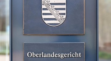 Aufsteller mit dem Wappen von Sachsen und der Aufschrift «Oberlandesgericht» am Gerichtsgebäude. Foto: Robert Michael/zb/dpa/Archivbild