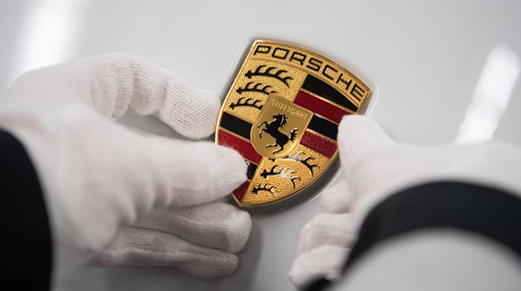 Eine Mitarbeiterin der Porsche AG hält in der Produktion ein Porsche-Emblem. Foto: Marijan Murat/dpa/Archivbild