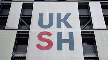 Das UKSH-Logo ist an einem Gebäude des Universitätsklinikums zu sehen. Foto: Carsten Rehder/dpa/Archivbild