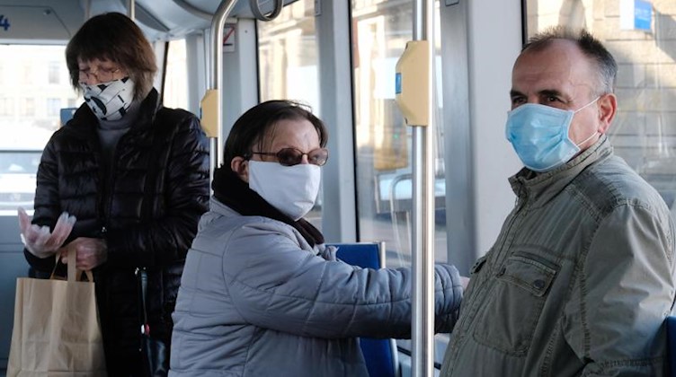 Fahrgäste stehen in einer Straßenbahn und tragen Mundschutz. Foto: Sebastian Willnow/dpa-Zentralbild/dpa