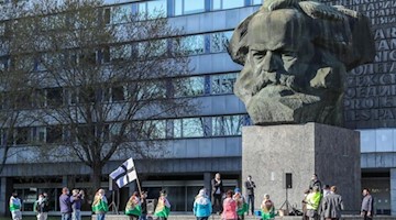 Teilnehmer der rechtsextremen Vereinigung Pro Chemnitz demonstrieren vor dem Karl-Marx-Monument. Foto: Jan Woitas/dpa-Zentralbild/dpa/Archivbild