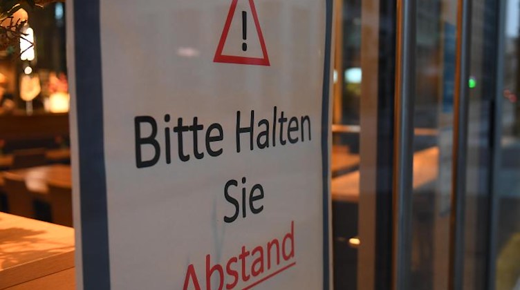 «Bitte Halten Sie Abstand» steht auf einem Schild am Eingang zu einer Bäckerei im Zentrum von Leipzig. Foto: Hendrik Schmidt/dpa-Zentralbild/ZB/Archivbild
