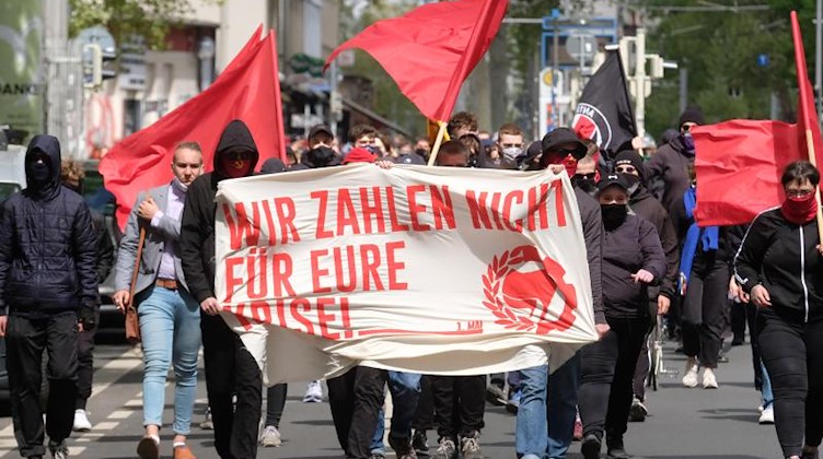 Teilnehmer einer linken Demonstration gehen mit Masken und einem Banner "Wir zahlen nicht für eure Krise!" über die Straße. Foto: Sebastian Willnow/dpa-Zentralbild/dpa
