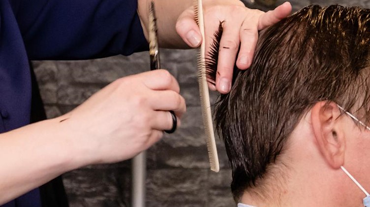 Eine Friseurin schneidet einem Kunden die Haare. Foto: Frank Molter/dpa
