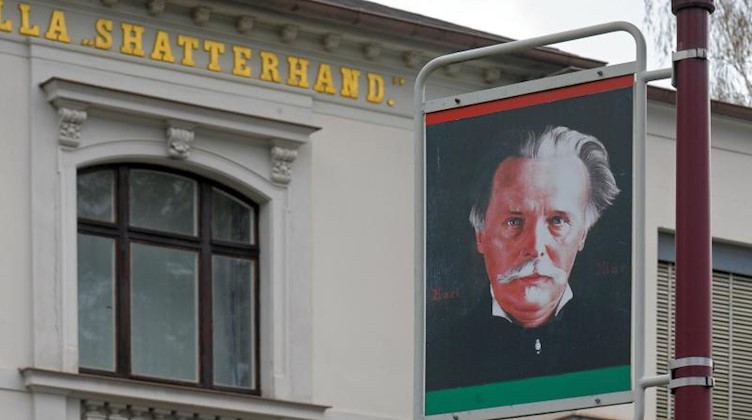 Ein Porträt des Schriftstellers Karl May hängt an einer Laterne vor dem Museum. Foto: Matthias Hiekel/dpa-Zentralbild/dpa/Archivbild