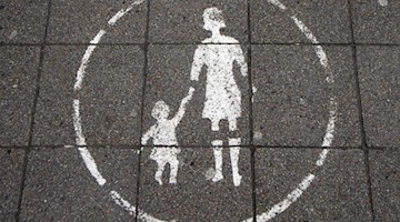 Ein Symbol einer Mutter mit einem Kind weist auf eine Fußgängerzone hin. Foto: picture alliance / dpa/Symbolbild