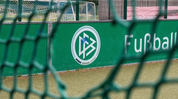Das Logo des Deutschen Fußball-Bundes DFB ist durch ein Loch im Tornetz zu sehen. Foto: Bernd Thissen/dpa/Archivbild