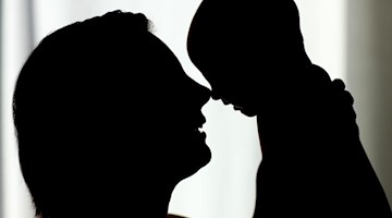 Eine Mutter hält ihr Baby hoch. Foto: Patrick Pleul/dpa-Zentralbild/dpa/Symbolbild