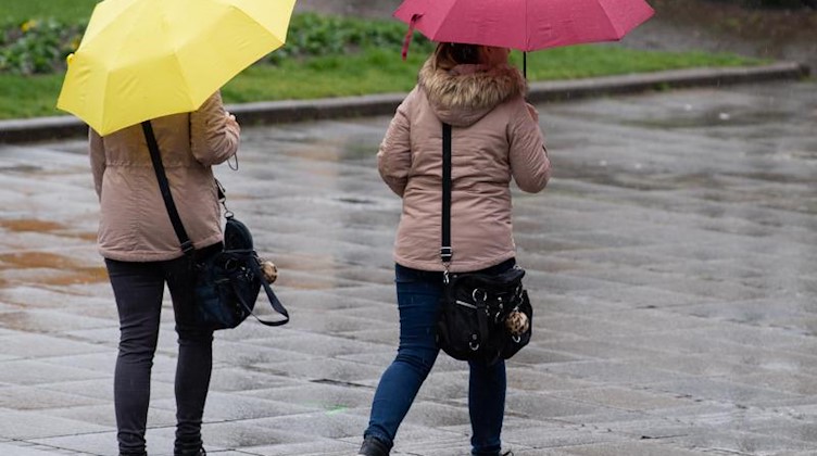 Zwei Frauen sind mit Regenschirmen unterwegs. Foto: Tom Weller/dpa/Symbolbild