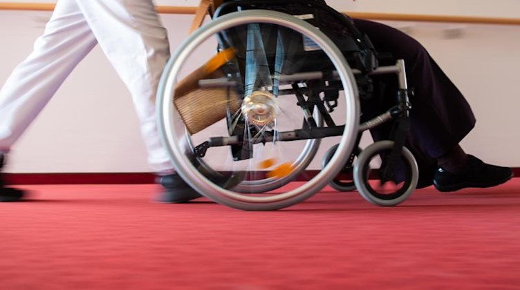 Ein Pfleger eines Pflegeheims schiebt eine Bewohnerin in einem Rollstuhl. Foto: Tom Weller/dpa/Symbolbild