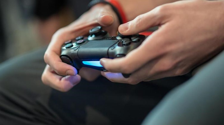 Ein Spieler hält ein Playstation Controller in der Hand. Foto: Guido Kirchner/dpa/Symbolbild