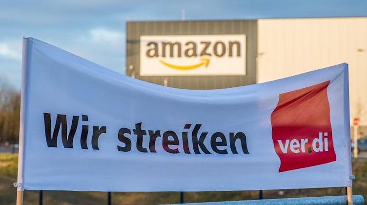 Verdi-Banner mit der Aufschrift «Wir streiken» vor einem Amazon-Logistik-Zentrum. Foto: Guido Kirchner/dpa/Archivbild