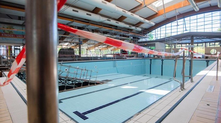 Absperrband hängt an einem Sportbecken in einem Schwimmbad. Foto: Julian Stratenschulte/dpa/Symbolbild