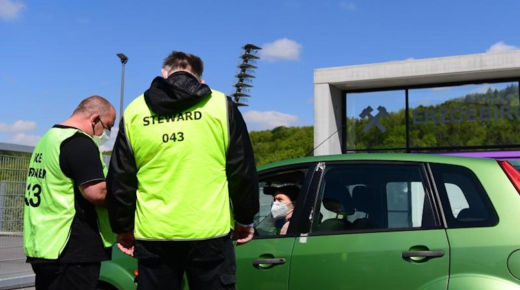Ordner kontrollieren einen Wagen an der Stadioneinfahrt. Foto: Robert Michael/dpa-Zentralbild - Pool/dpa