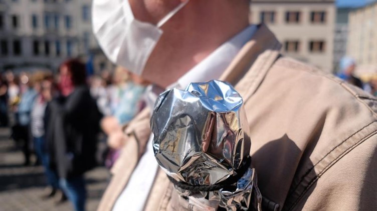 Ein Demonstrant trägt Silberfolie in der Brusttasche - das Erkennungszeichen der Corona-Skeptiker. Foto: Sebastian Willnow/dpa-Zentralbild/dpa