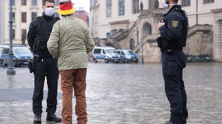 Polizisten stehen auf dem Neumarkt vor einem Mann mit einem schwarz-rot-goldenem Anglerhut. Foto: Sebastian Kahnert/dpa-Zentralbild/dpa