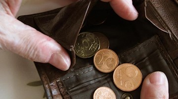 Eine Frau hält eine nahezu leere Geldbörse in den Händen. Foto: Jens Kalaene/dpa-Zentralbild/dpa/Illustration