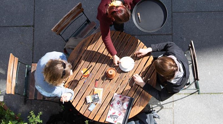 Eine Kellnerin bedient in einem Cafe zwei Frauen. Foto: Sebastian Kahnert/dpa/Archivbild