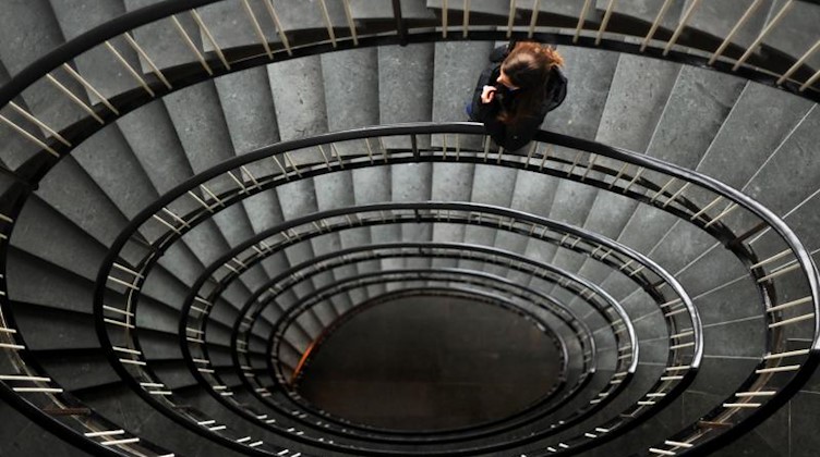 Eine Frau steht in einem Treppenhaus. Foto: Julian Stratenschulte/dpa/Illustration
