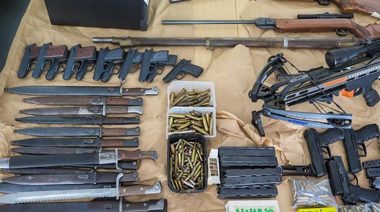 Sichergestellte Waffen und Munition liegen auf einem Tisch. Foto: Polizeipräsidium Mittelhessen/dpa