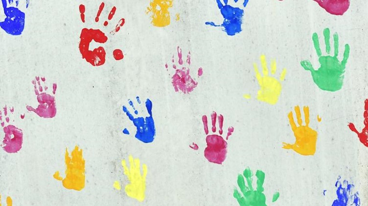 Bunte Handabdrücken auf einer bemalte Wand einer Kindertagesstätte. Foto: Peter Kneffel/dpa/Archivbild