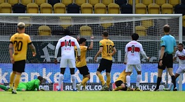 Darko Churlinov (r.) von Stuttgart erzielt das 0:2 gegen Torwart Kevin Broll (2.v.l) von Dresden. Foto: Robert Michael/dpa-Pool/dpa