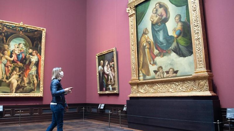 Eine Frau steht in der Gemäldegalerie Alte Meister vor dem Gemälde «Sixtinische Madonna» (r) von Raffael. Foto: Sebastian Kahnert/dpa-Zentralbild/dpa/Archivbild