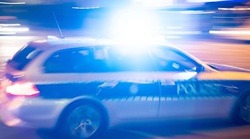Ein Polizeiauto fährt unter Einsatz von Blaulicht und Sirene eine Straße entlang. Foto: Lino Mirgeler/dpa/Symbolbild