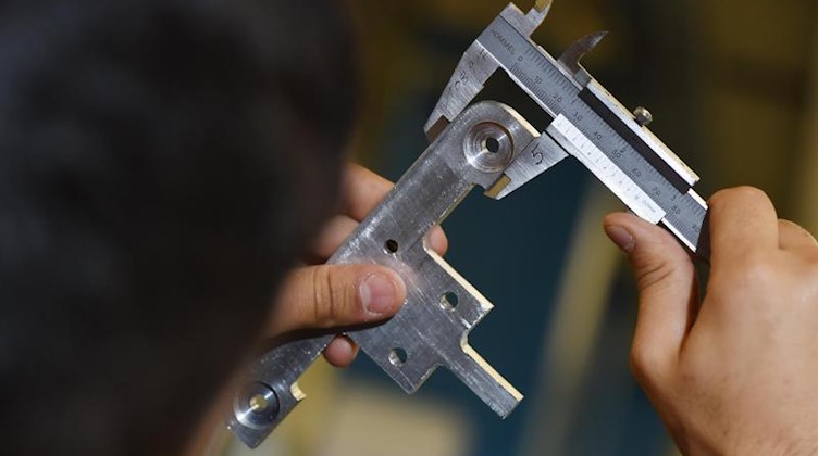 Ein Handwerker misst ein Werkstück mit einer Schieblehre aus. Foto: Felix Kästle/dpa/Symbolbild