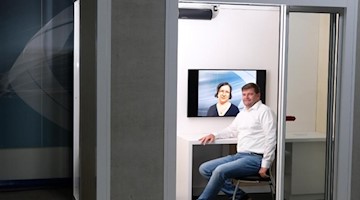 Geschäftsführer der Seiwo Technik GmbH sitzt in flexiblem Corona-Schutzraum, dem «Protect Cube». Foto: Sebastian Willnow/dpa-Zentralbild/dpa