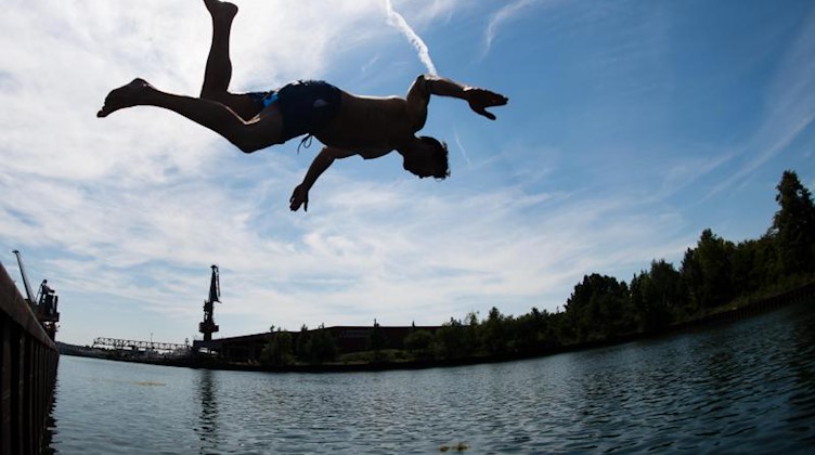 Ein Mann springt ins kühle Nass. Foto: Julian Stratenschulte/dpa/Symbolbild