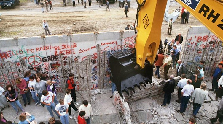 Ein Schaufelbagger reißt die Berliner Mauer an der Bernauer Straße ein. Foto: picture alliance / dpa/Archivbild