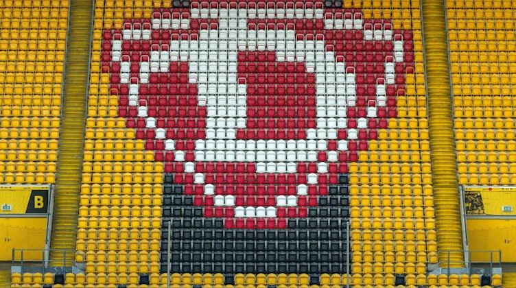 Hochgeklappte Sitze und das Logo des SG Dynamo Dresden sind im Rudolf-Harbig-Stadion zu sehen. Foto: Robert Michael/dpa-Zentralbild/dpa/Archivbild
