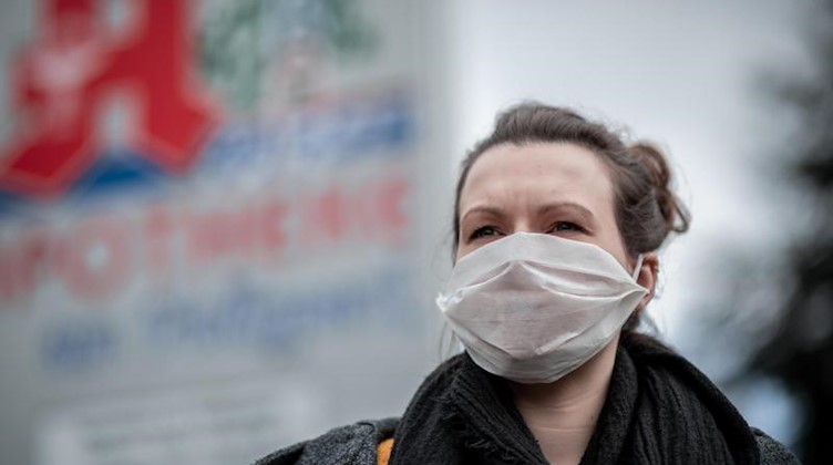 Eine Frau trägt vor einer Apotheke eine Mund- und Nasenmaske. Foto: Fabian Strauch/dpa/Archivbild