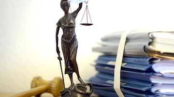 Justitia mit Holzhammer und Aktenstapel. Foto: Volker Hartmann/dpa/Symbolbild