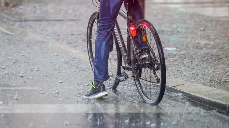 Ein Radfahrer steht im strömenden Regen an einer Ampel. Foto: Jan Woitas/dpa-Zentralbild/dpa/Archivbild