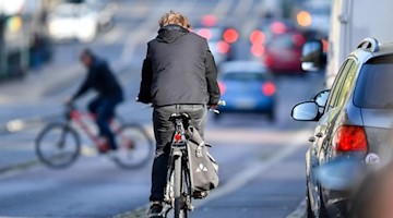 Radfahrer sind neben Autos im Zentrum von Halle unterwegs. Foto: Hendrik Schmidt/dpa-Zentralbild/dpa/Archivbild
